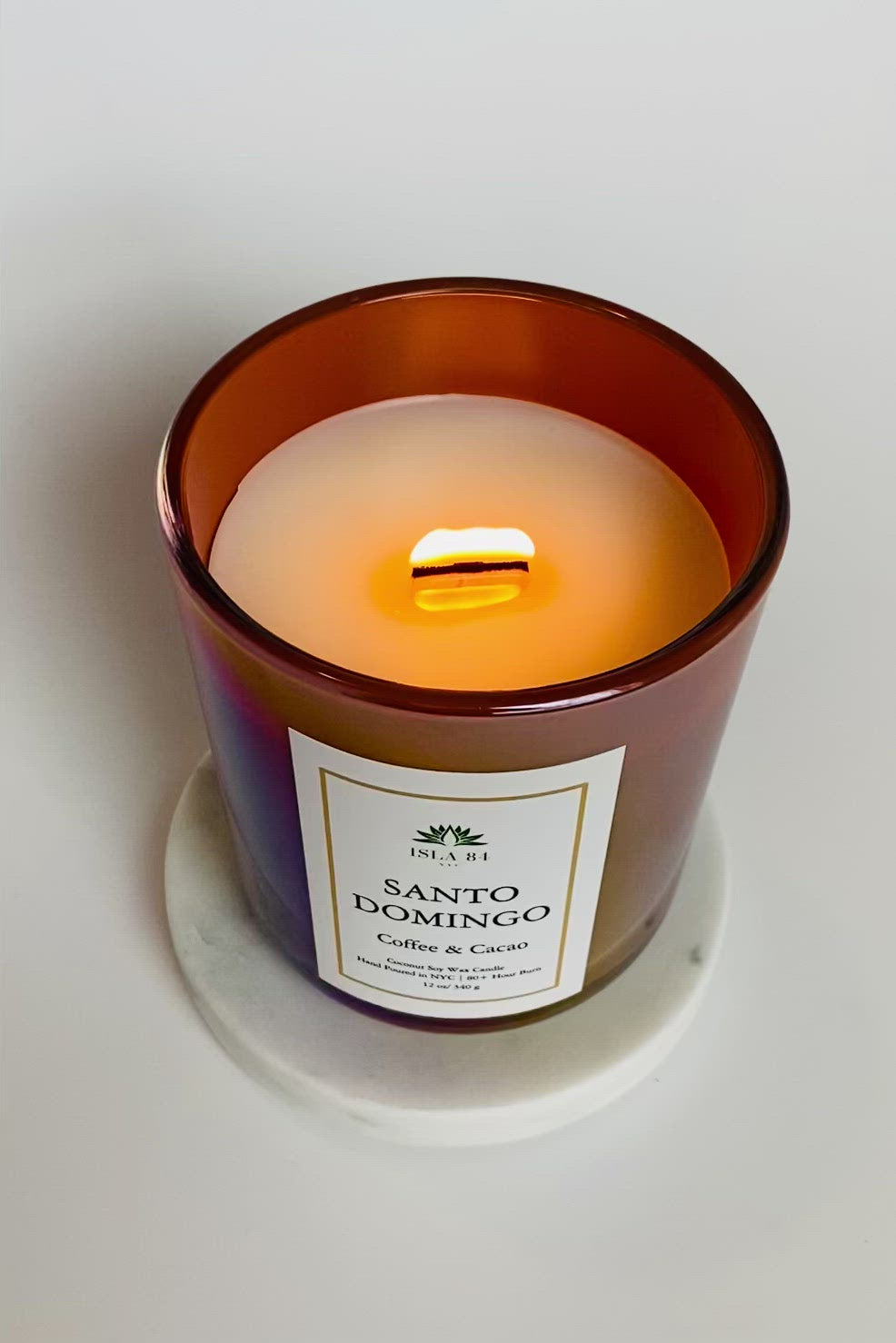 Santo Domingo Scented Candle; Saint Sunday; Dominican Republic Candles; DR Candles; Quisqueya Candles; Velas aromaticas; Coconut Soy Wax Candles; Iridescent Brown Vessel with White label and green logo; burning wood wick