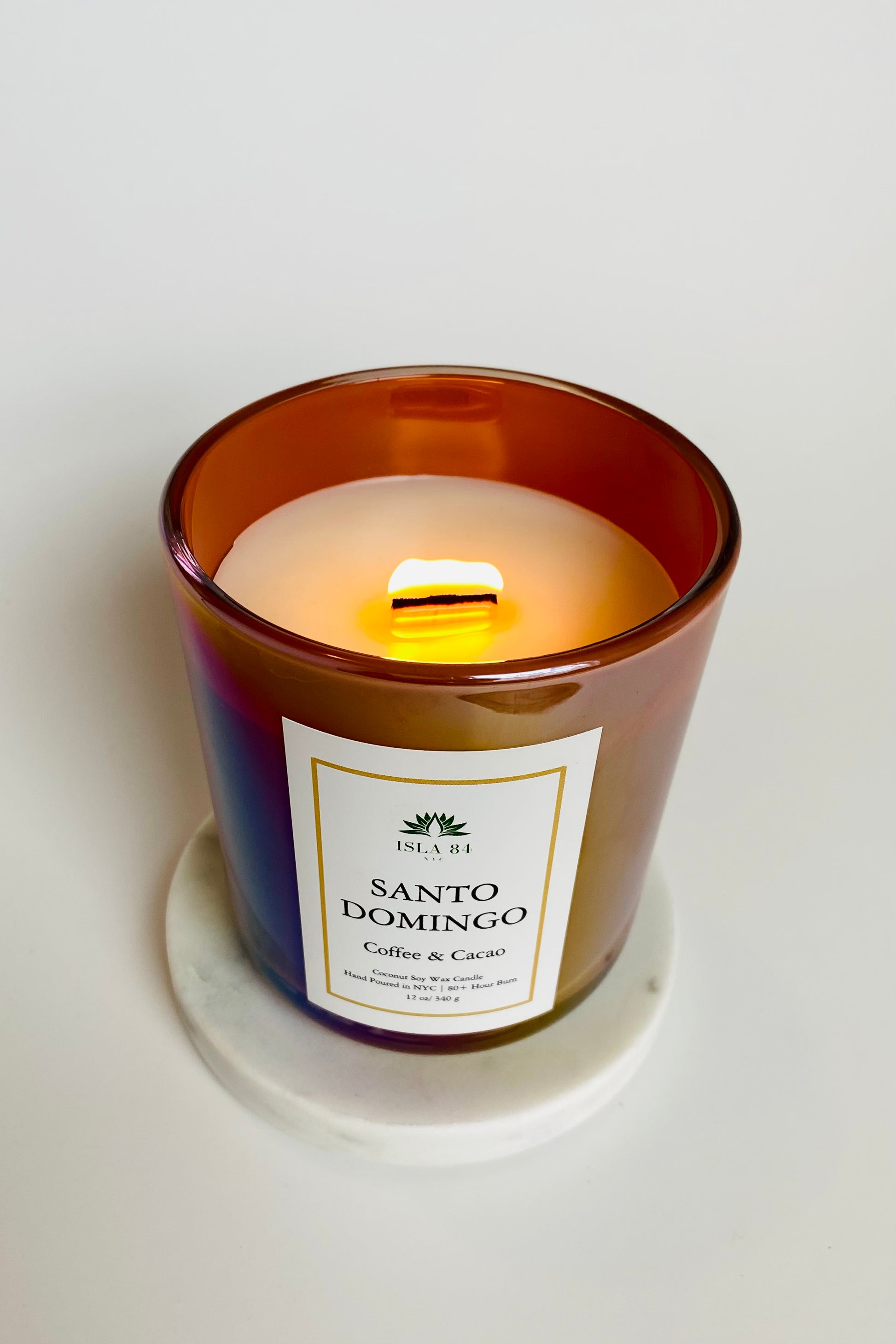 Santo Domingo Scented Candle; Saint Sunday; Dominican Republic Candles; DR Candles; Quisqueya Candles; Velas aromaticas; Coconut Soy Wax Candles; Iridescent Brown Vessel with White label and green logo; Burning wood wick